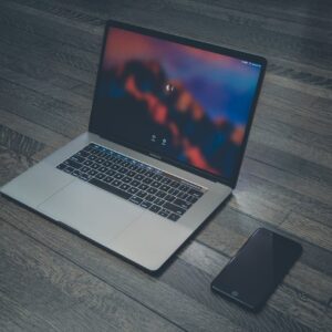 A sleek laptop and smartphone placed on wooden flooring, showcasing contemporary technology.